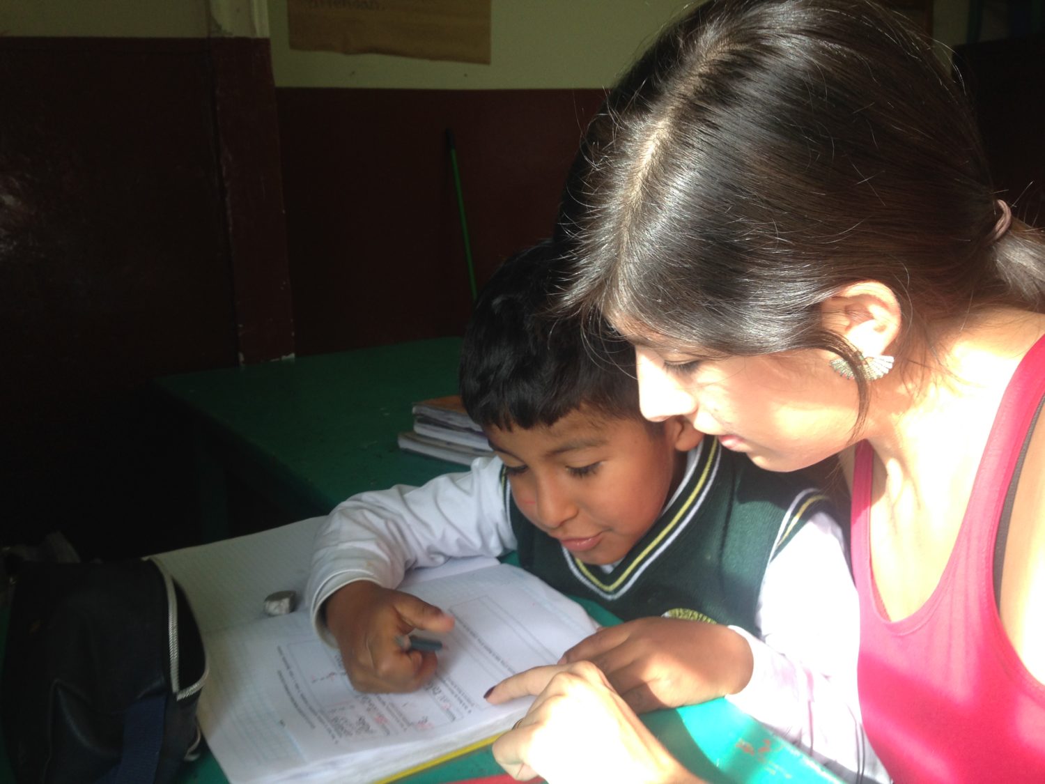 Junge Frau hilft Schüler bei den Hausaufgaben