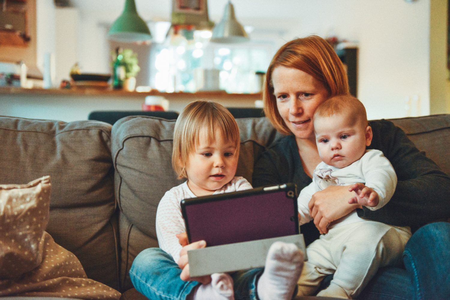 Eine Familie sitzt zu Hause auf dem Sofa und schaut sich das iPad an