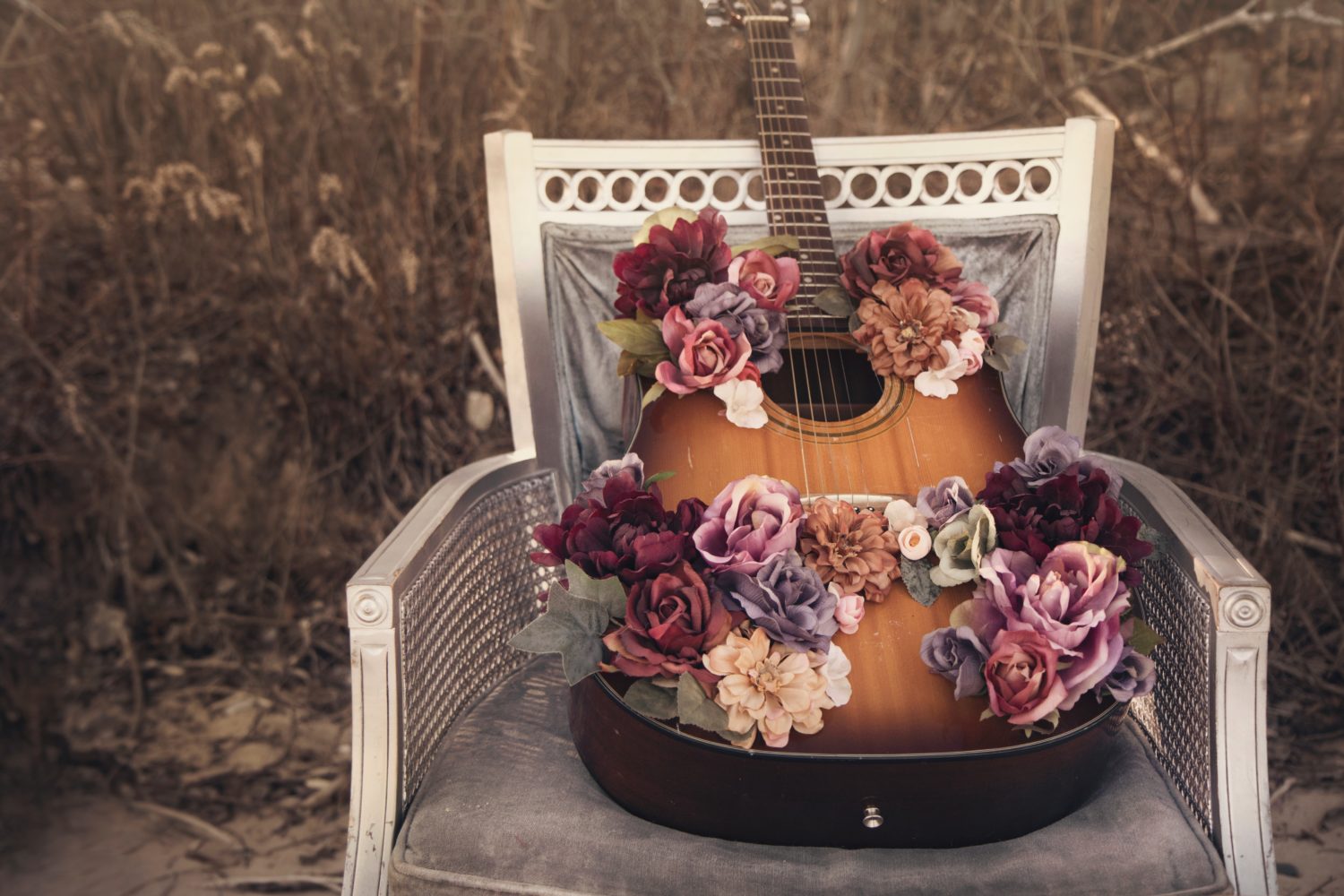 Stuhl auf der eine Gitarre, die mit Blumen dekoriert ist, liegt. 