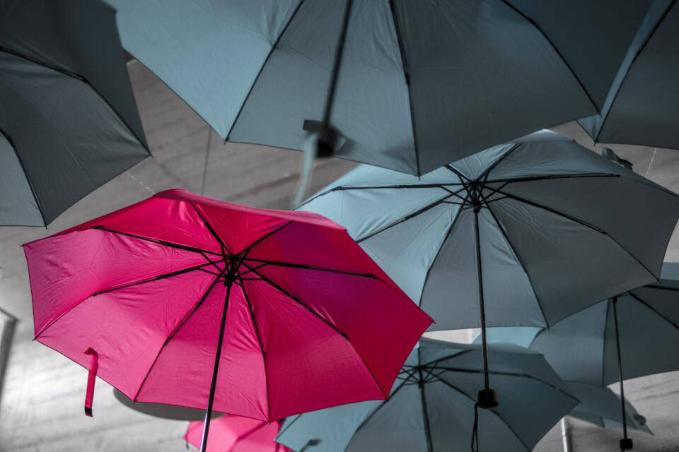 Pink umbrella among gray umbrellas