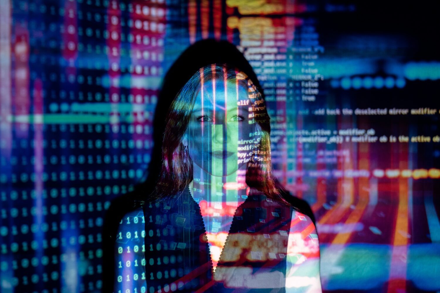 Eine Frau im Metaverse - bunte Lichtströme und Daten verlaufen im Hintergrund und über ihr Gesicht