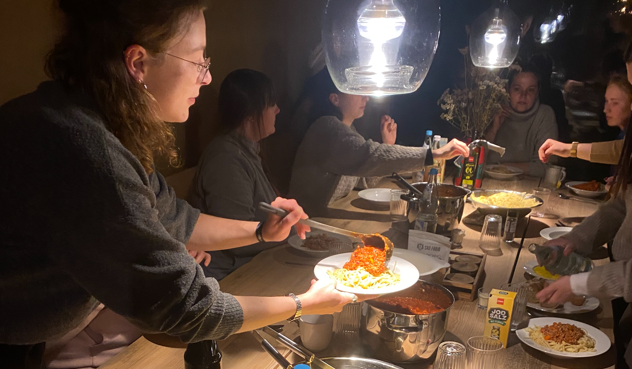 Ein Teammitglied füllt beim gemeinsamen Abendessen einen Teller auf